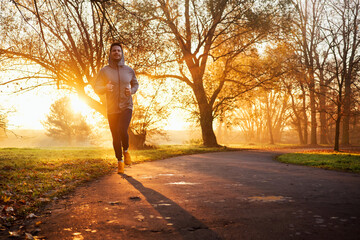 Adult male running in park at autumn sunny morning