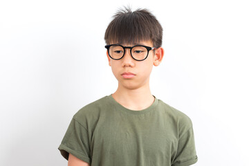 Frowning asian schoolboy wear glasses with serious look standing on white background.