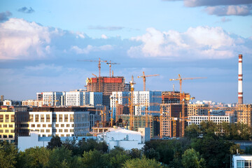 Buildings under construction and tower cranes. Construction site of multistory blocks of flats