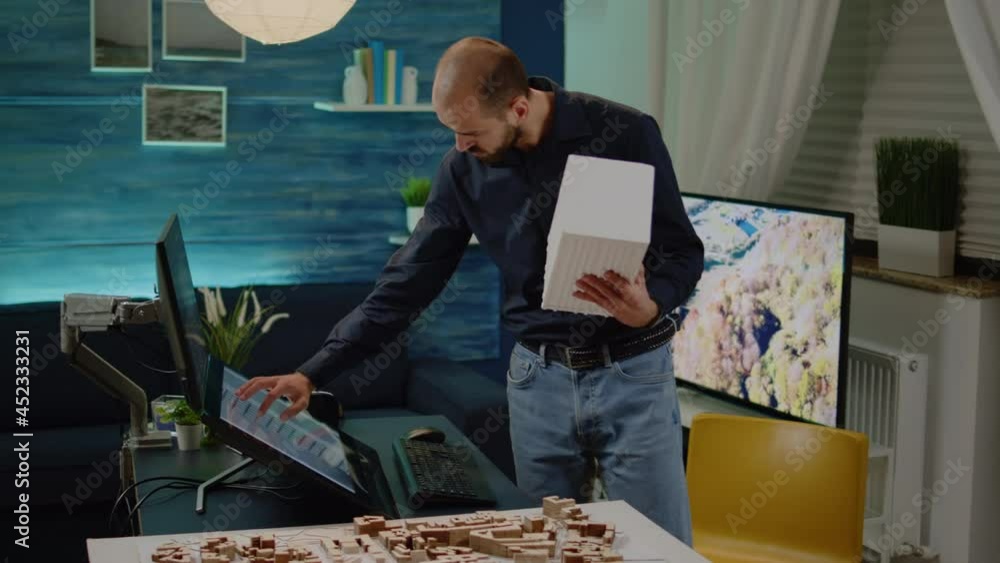 Poster man architect checking maquette in hand with model on monitor. engineer using touch screen for build