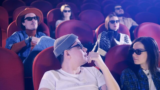 Rude man puts his feet up and throws popcorn at the movie theater