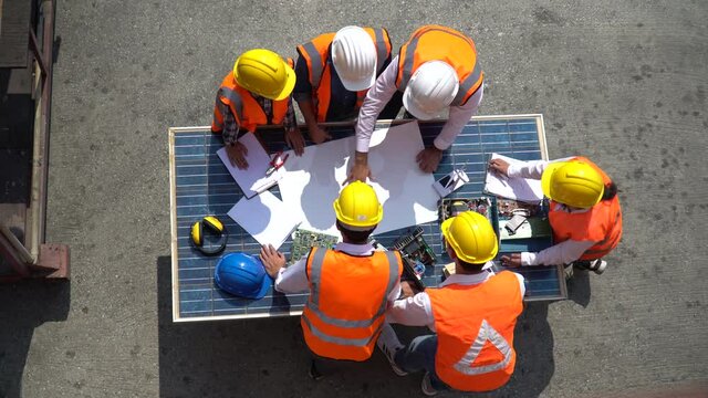 Group of Solar power plant Engineers Team Meeting and discussion to brainstorming with blueprint on solar cell top table Planning for a New Project of Environmental Power at construction site outdoors