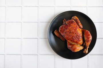 Grilled chicken with a delicious fried crust on a black plate. Chicken cooked on the fire. Barbecue chicken. Bbq. Baked bird.