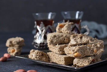 Sweet sunflower halva with peanut on metal tray on dark gray background. Horizontal format