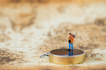 Miniature people Group of young tourist traveler traveling standing on golden compass travel around the world, business trip traveler adviser agency or online world wide marketing new transportation