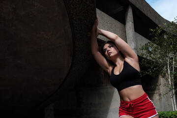 Attractive young fitness woman stretching in an urban environment.