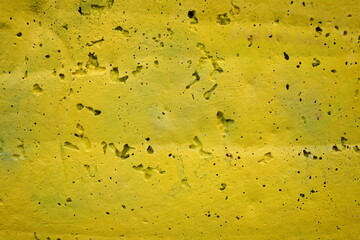 The concrete wall  with small dark spots.  The texture of building concrete. Yellow background, copy space.