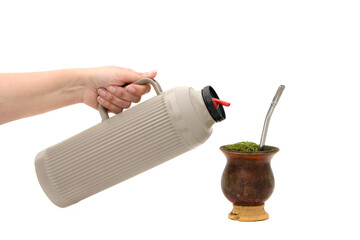Mão segurando uma garrafa térmica, pronta para colocar água na cuia de chimarrão, bebida...