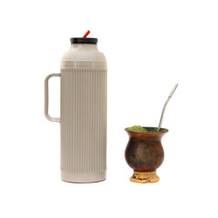 Garrafa térmica plástica ao lado uma cuia com erva-mate e bomba velhas, usadas para o preparo do...