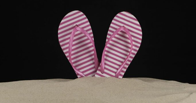 Beach flip flops sticking out of the sand. Slider shot. Isolated.
