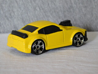 Fototapeta na wymiar Car miniature, sedan toy for kids withyellow paint and black tires with turbo engine.