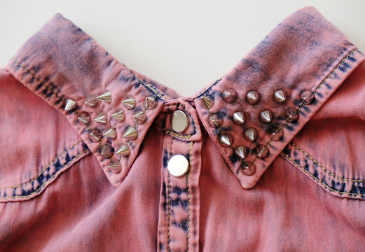 Pink denim collar with metal studs and buttons close up. White background