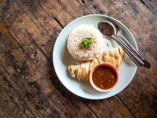 Chicken rice, Thai food, high angle There is rice and boiled chicken on a high angle white plate on a wooden table. There is space for text.