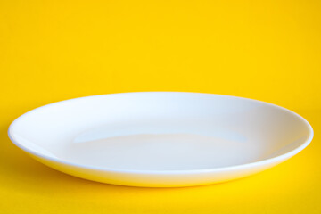 empty white plate on yellow background