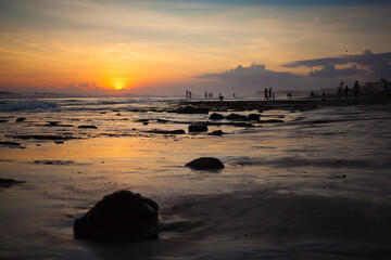 Fototapeta na wymiar Silhouettes of rock, reef and people at sea sunset