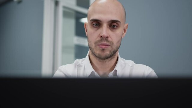 Young man starting his working day in office, open up a laptop cover and answer a phone call. Gimbal shot closeup, office manager and devices