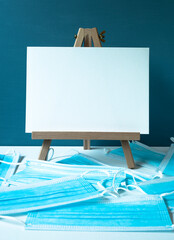 wooden easel with white board with space for text, blue medical masks