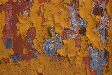 Textured background of rough rusty metal wall with red and yellow peeling paint 