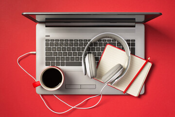 Above photo of grey laptop cup of coffee notebook with pencil and headphones isolated on the red...