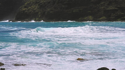 Blue Waves of the Pacific Ocean Beats Oahu Island Volcanic Cliffs. Turquoise water color. Clear...