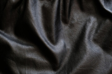 Wavy black leather fabric background, texture. Space for design.