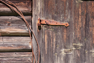 Texture of old logs and door on the wall of a rustic wooden building