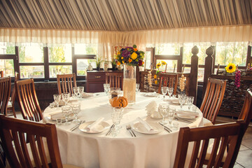 Festive floristry in autumn style with numbering of tables on pumpkins in banquet hall.