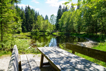 ein romantischer See im Wald mit Bank und Tisch aus Holz 