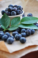 Freshly picked blueberries in a white bowl. Juicy and fresh blueberries with green leaves. Antioxidant. Healthy food concept. Healthy organic seasonal fruits background.