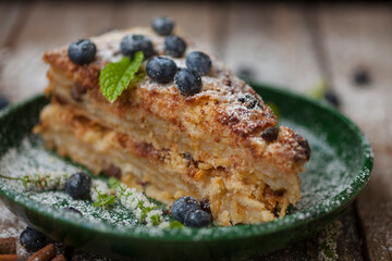 Green plate with delicious slice of cake  on wooden background