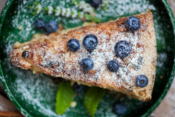 Green plate with delicious cake on wooden background
