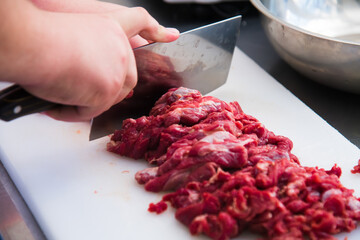 Professional chef finely cuts the meat with a large knife. Food preparation