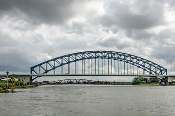 Zwolle, the Netherlands, August 10, 2021: view along the IJssel river with the historic arch bridge and beyound it the new Hanzeboog bridge, under a dramatic sky