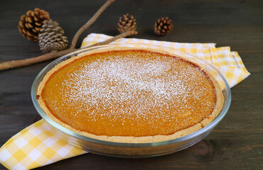 Delectable Homemade Pumpkin Pie Sprinkled with Powdered Sugar on Wooden Table