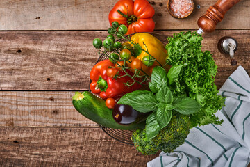 Fresh cherry tomato branches, basil leaves, napkin, pepper and pepper mill on old wooden rustic background. Food cooking background and mock up.