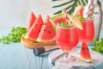 Watermelon cocktail with mint and ice. Summer refreshing drinks in glasses on blue wooden table. Concept of healthy summer eating.