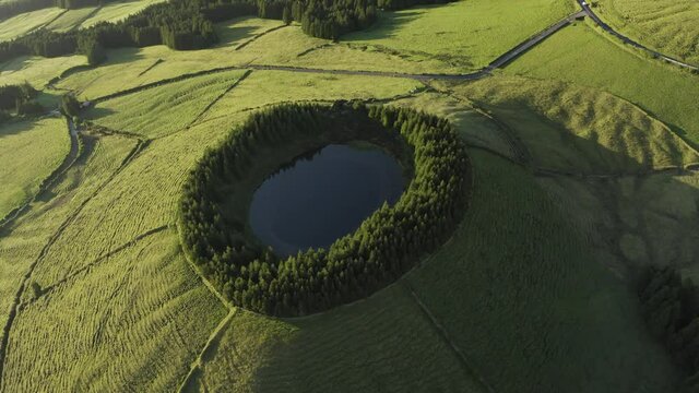 Aerial view of Lagoa das Eguas, a small lake on hilltop at sunset on Sao Miguel Island, Azores island, Portugal.