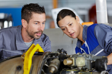 confused male and female mechanic examining car engine