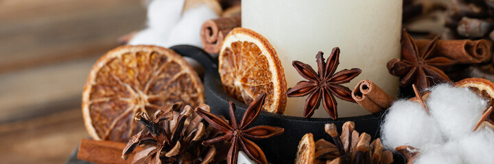 Rustic decor for christmas family dinner. Center piece with white candle, dry orange, cone, cotton. Zero waste eco-friendly home decoration. Cozy atmosphere, wooden background. Close up banner