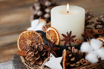 Rustic decor for christmas holiday family dinner. Center piece with white candle, dry orange, cones, cotton. Zero waste eco friendly home decoration. Cozy atmosphere, wooden background. Close up