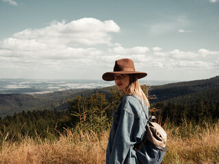 Woman in hat looking on nature, forest and clouds