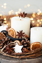 Fototapeta na wymiar Rustic decor for christmas holiday family dinner. Center piece with white candle, dry orange, cones, cotton. Zero waste eco friendly home decoration. Cozy atmosphere, wooden background. Close up