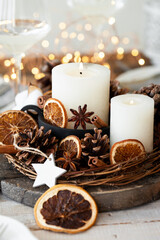 Rustic decor for christmas holiday family dinner. Center piece with white candle, dry orange, cones, cotton. Zero waste eco friendly home decoration. Cozy atmosphere, wooden background. Close up
