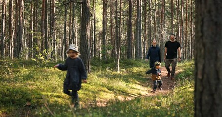happy young family enjoying walk in forest. running children