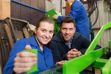 portrait of male and female workers by industrial machine