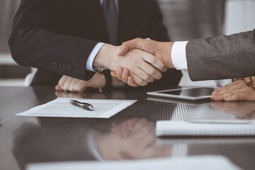 Handshake as successful negotiation ending, close-up. Unknown business people shaking hands after contract signing in modern office