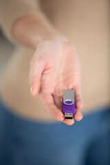 young woman hands holding purple flash drive