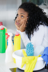 tired woman next to cleaning products