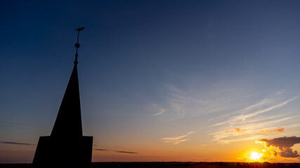 Kirche und Kirchturm im Sonnenuntergang mit weiter Landschaft und Natur im Hintergrund