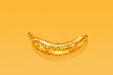 Creative golden banana with glitter on yellow background with copy space © SOLDATOOFF